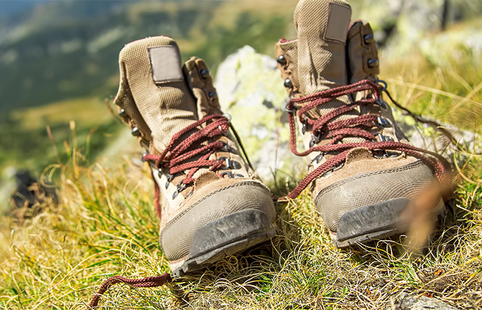 This image shows a pair of hiking boots on a grassy hill.