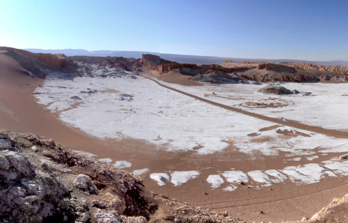 The image shows the salt rich Valle de la Muerte with a clear blue sky.
