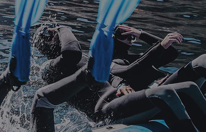 This image shows divers flip backwards from a rubber boat at the Galapagos Islands